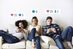 Young adults on the couch using social media on their smartphones Trendy w social mediach w 2026 roku